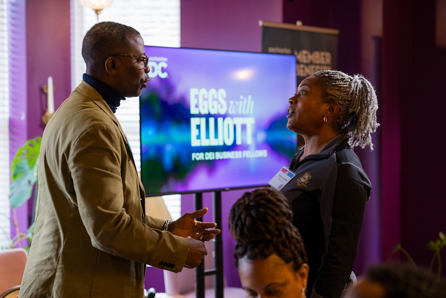 Man talking to with a woman with a screen in the background