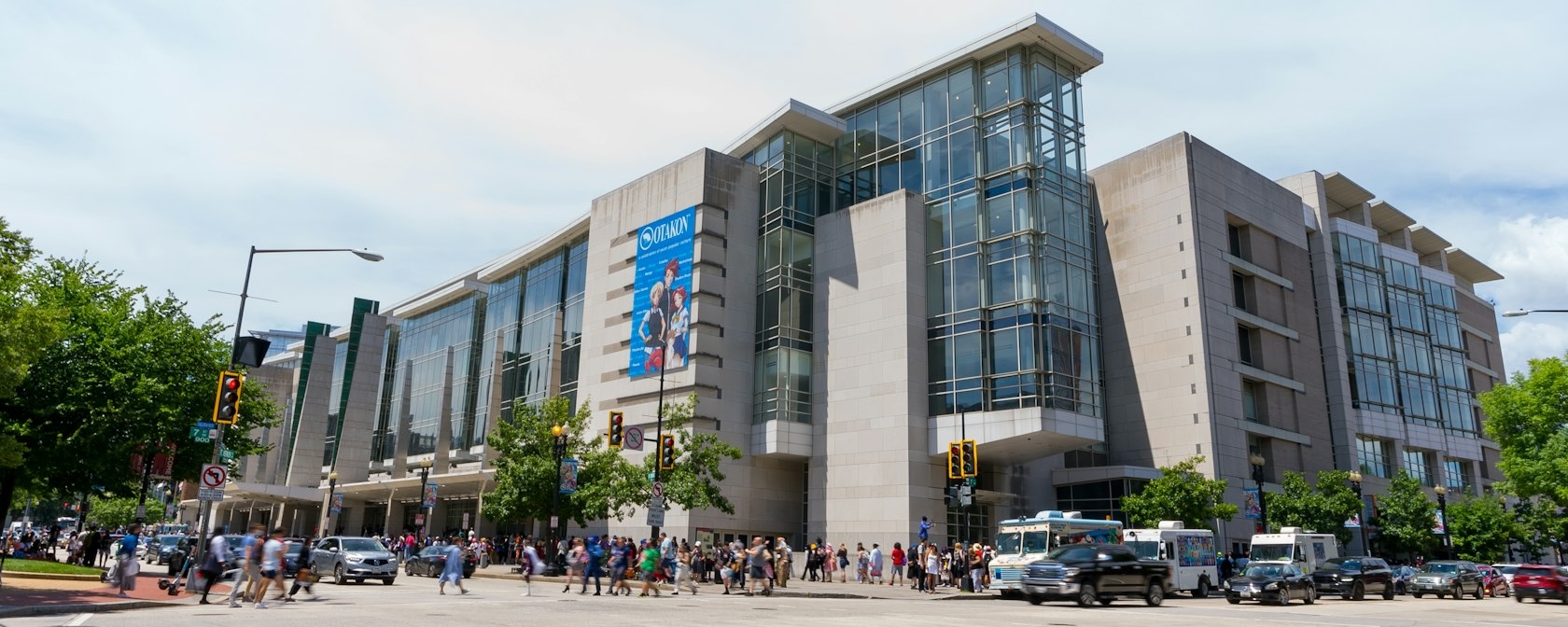 The exterior of the Walter E. Washington Convention Center on a bright day with crowds walking along the street.