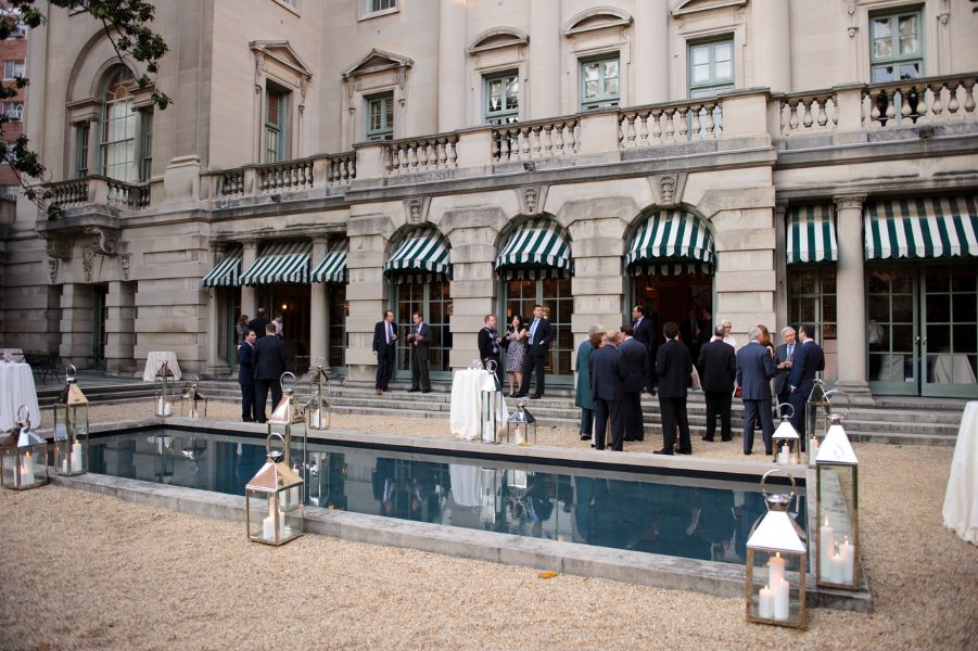 Backyard with fountain and groups of people having happy hour in suits