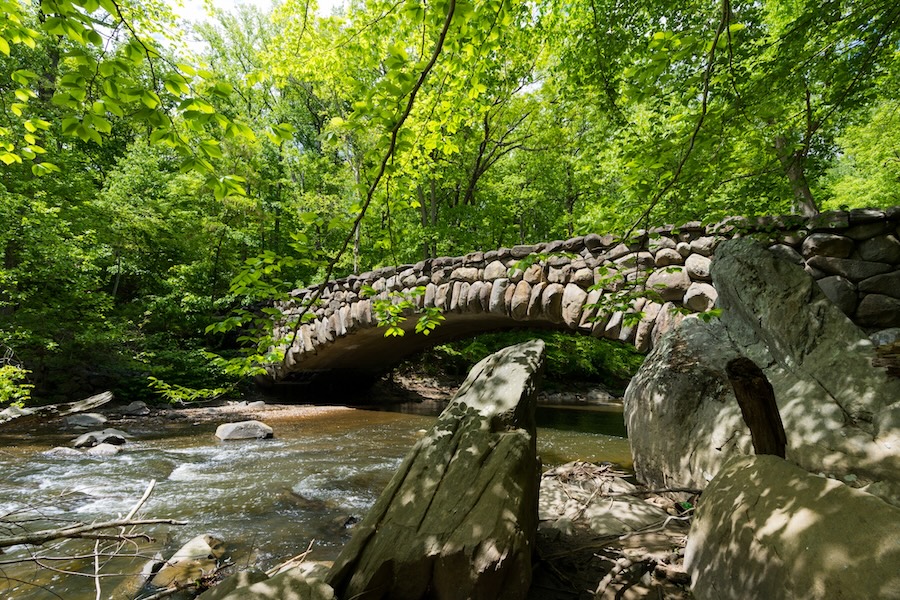 A stone arch bridge spans a wooded creek in Rock Creek Park, Washington, DC.