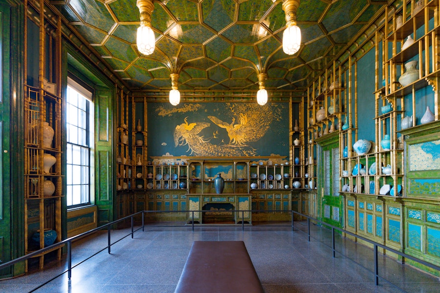 The Peacock Room at the Freer Gallery decorated with blue-green walls, gold accents and porcelain displays.