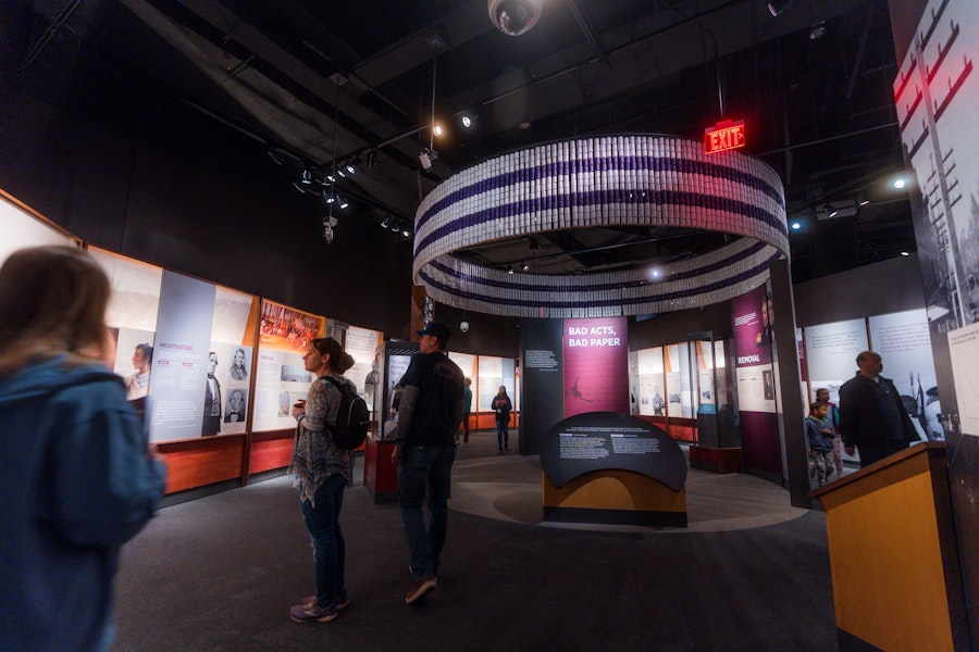 Visitors exploring the “Bad Acts, Bad Paper” exhibit inside the National Museum of the American Indian.