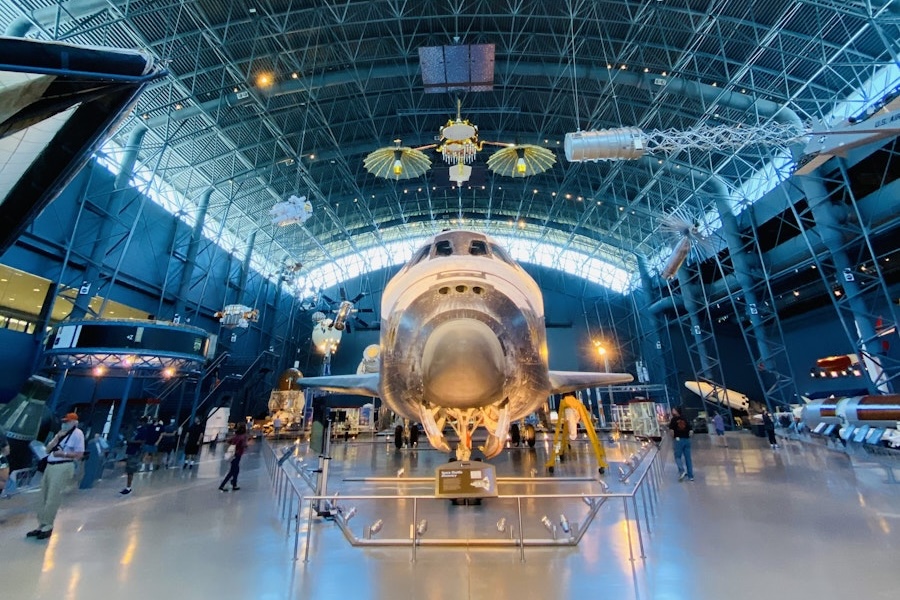 Front view of the Space Shuttle Discovery under an American flag at the Smithsonian Udvar-Hazy Center.