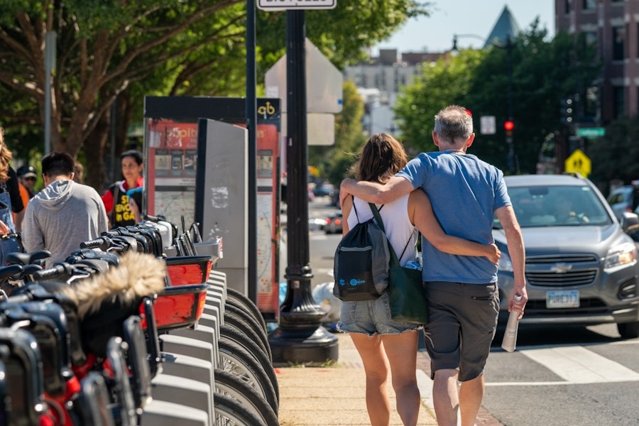 A couple walks arm in arm past a row of Capital Bikeshare bikes in the Adams Morgan neighborhood of Washington, DC.