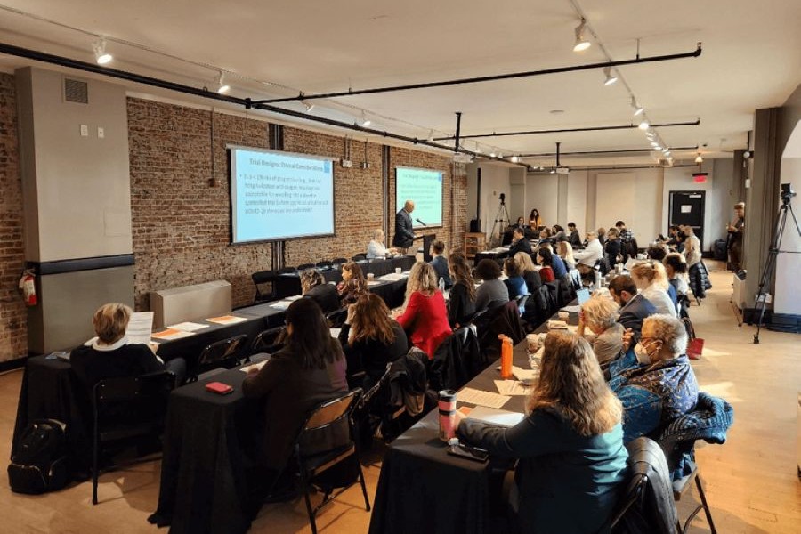 Attendees listen to a speaker giving a presentation in a brick-walled conference room at the National Union Building.