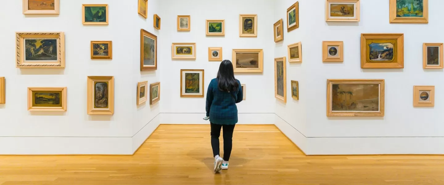  A visitor explores a gallery at The Phillips Collection, where small framed paintings in various styles are arranged on white walls, creating an immersive art experience.