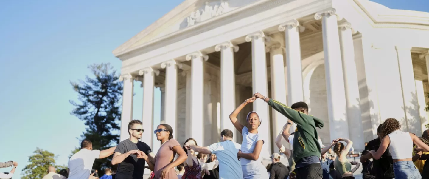 People dance on the steps of the Jefferson Memorial.