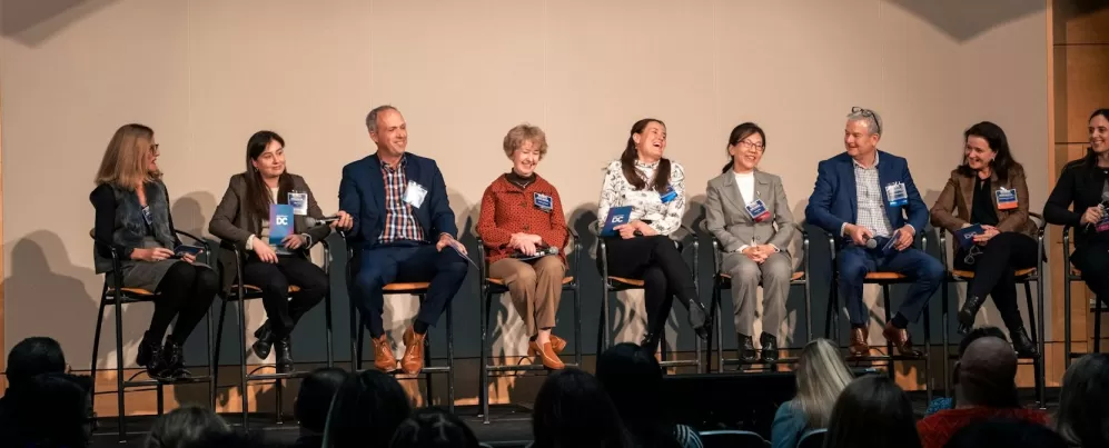 A stage of professional panelists smiling and laughing. 