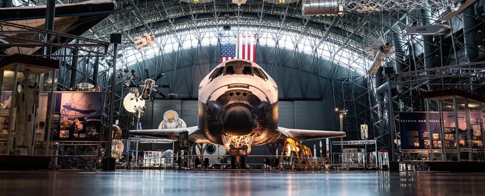 The Space Shuttle Discovery displayed inside the Smithsonian’s Steven F. Udvar-Hazy Center with spacecraft exhibits surrounding it.